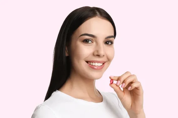 Smiling woman holding an Accutane pill for acne treatment